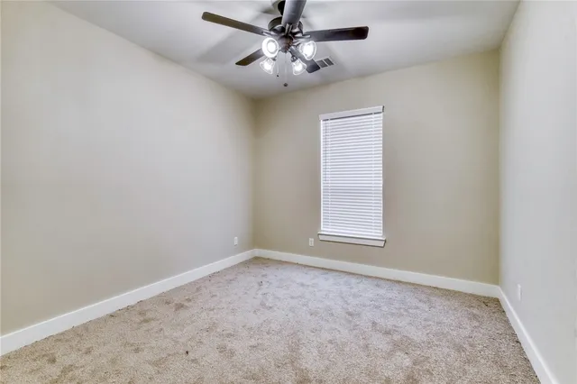 an empty room with a window and a fan