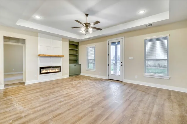 a view of an empty room with a window and a kitchen