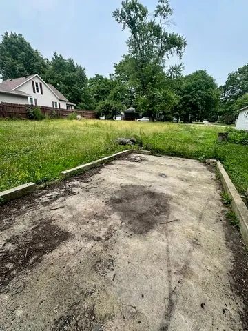 a view of a road with a big yard and large trees