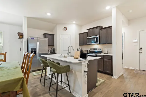 a kitchen with stainless steel appliances a table chairs refrigerator and microwave