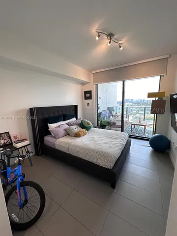 a bedroom with a bed a couch and large window