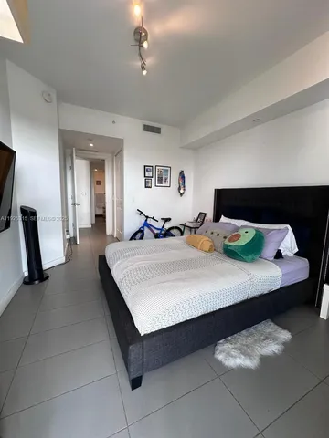 a bedroom with a large bed and a flat tv screen