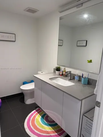 a bathroom with a granite countertop sink and a toilet