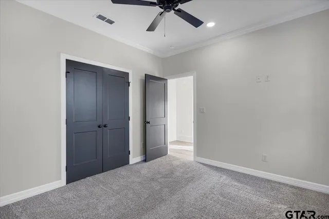 a view of an empty room and chandelier fan
