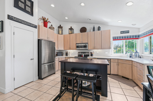31 Village Square Road Centerville, UT 84014 - Photo 11 of 29 Spacious kitchen featuring an island with seating, stainless steel appliances, light-toned cabinetry, light countertops, and tile flooring
