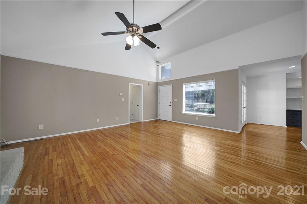7032 Cambridge Circle Tega Cay, SC 29708 - Photo 8 of 36 an empty room with wooden floor chandelier fan and windows