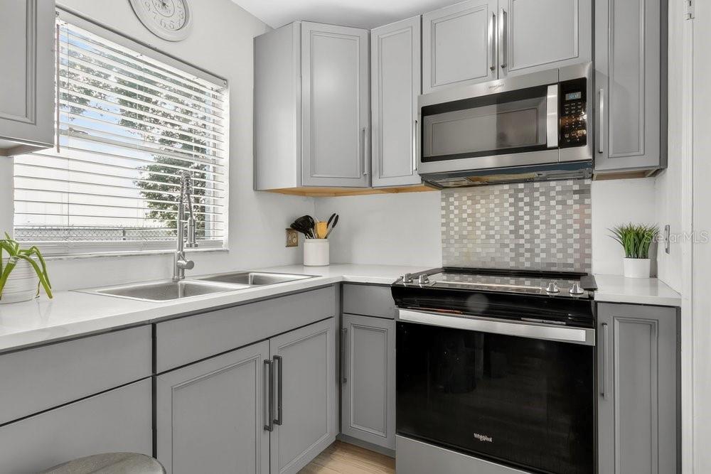 4227 Pershing Pointe Place, Unit 2 Orlando, FL 32822 - Photo 7 of 34 a kitchen with granite countertop white cabinets stainless steel appliances and a sink