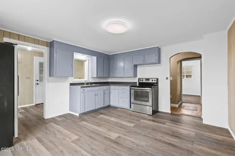 a kitchen with granite countertop a refrigerator and a stove top oven