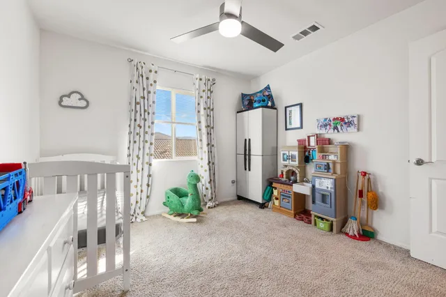 a view of a bedroom with baby crib and a chandelier