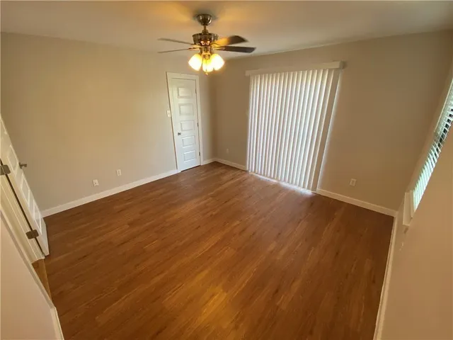 a view of a room with wooden floor and ceiling fan