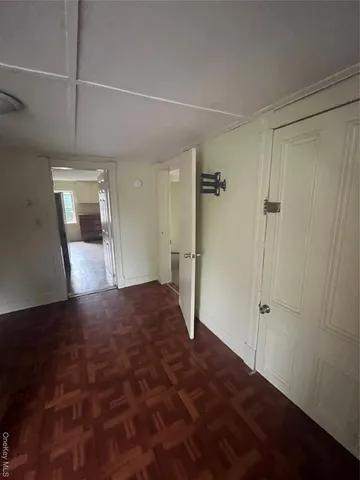 a view of a hallway with wooden floor and cabinet