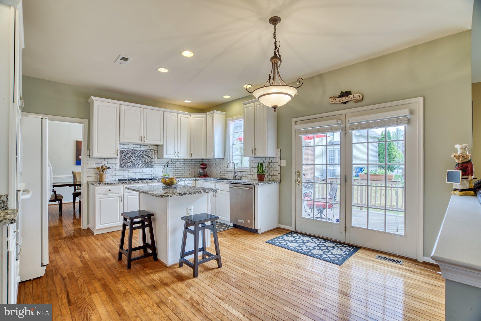 10855 Hunter Gate Way Reston, VA 20194 - Photo 7 of 57 a open kitchen with stainless steel appliances granite countertop a stove top oven a refrigerator a sink and a dining table with wooden floor