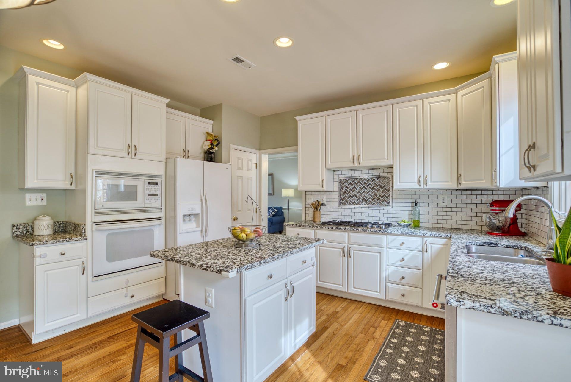 10855 Hunter Gate Way Reston, VA 20194 - Photo 9 of 57 a kitchen with kitchen island granite countertop white cabinets and white appliances