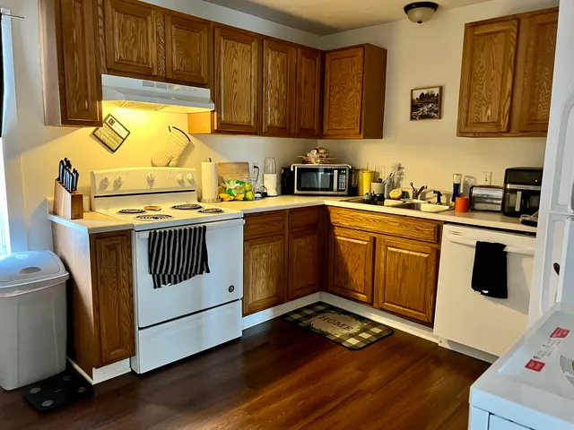 a kitchen with a stove a sink wooden floor and a window