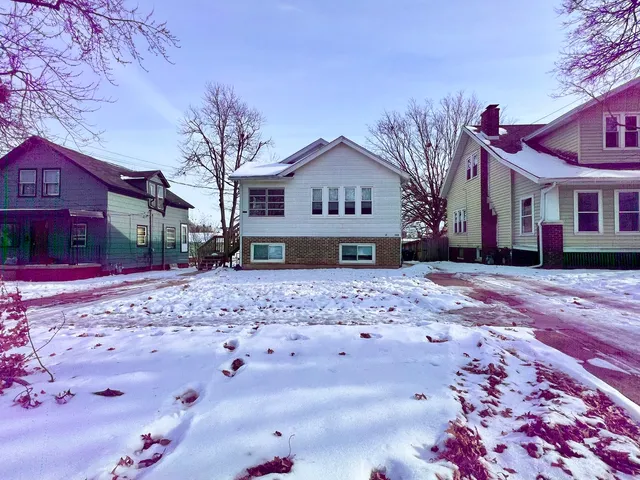 a front view of a house with a yard covered with snow
