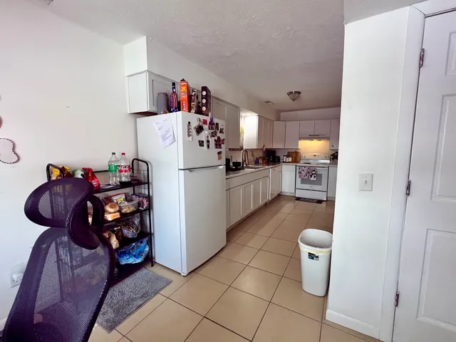 a living room with furniture and a refrigerator
