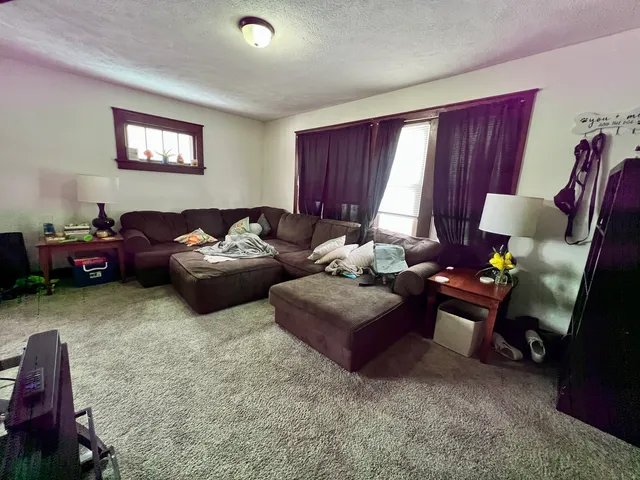 a living room with furniture two window and a flat screen tv