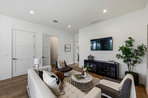 a living room with furniture a potted plant and a flat screen tv