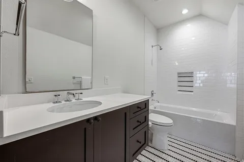 a bathroom with a granite countertop sink toilet mirror and bathtub
