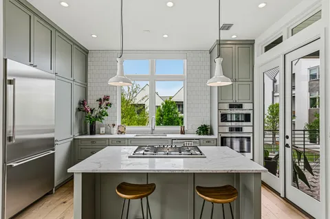 a kitchen with stainless steel appliances granite countertop a table chairs and a refrigerator