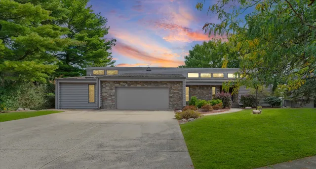 a front view of a house with a garden and trees