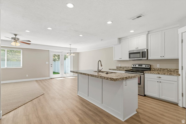 847 225 South Springville, UT 84663 - Photo 4 of 23 Kitchen and living area featuring wood-finish flooring, white cabinetry, a kitchen island with seating, stainless steel appliances, and recessed lighting