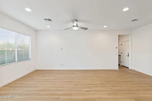 an empty room with wooden floor ceiling fan and windows