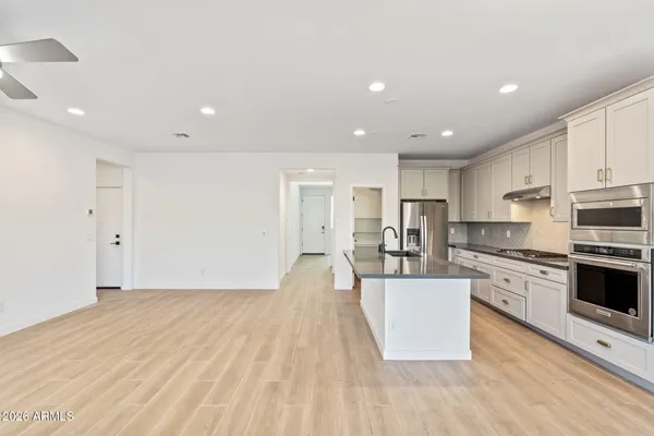 a large kitchen with stainless steel appliances granite countertop a large center island a stove a refrigerator white cabinets and wooden floor