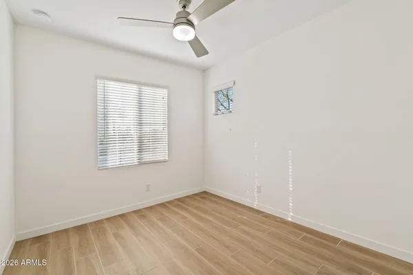 an empty room with wooden floor fan and windows