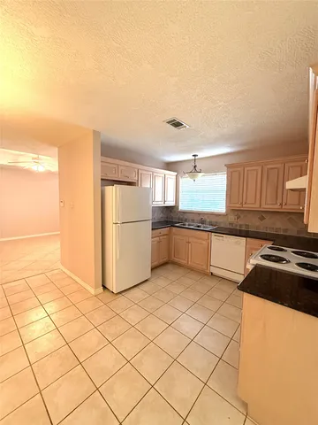 a kitchen with granite countertop a refrigerator and a stove top oven