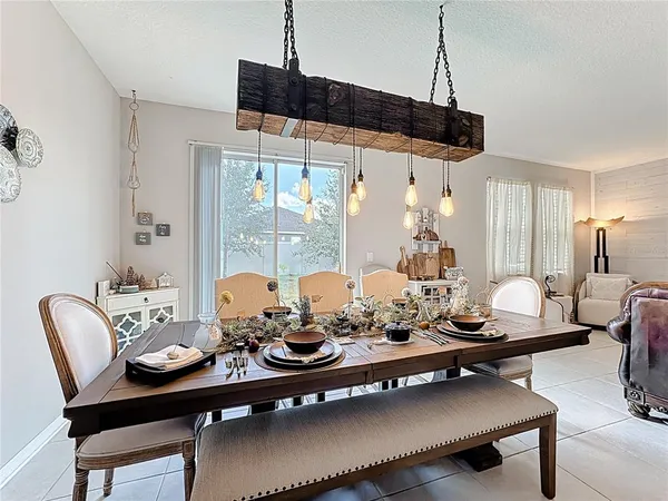 a view of a dining room and livingroom with furniture wooden floor a rug a flat screen tv a painting and a chandelier