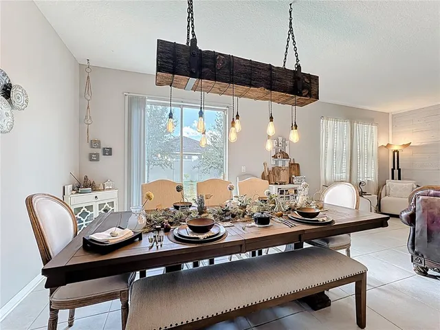 a view of a dining room and livingroom with furniture wooden floor a rug a flat screen tv a painting and a chandelier