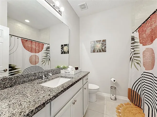 a bathroom with a granite countertop double vanity sink a mirror and a shower