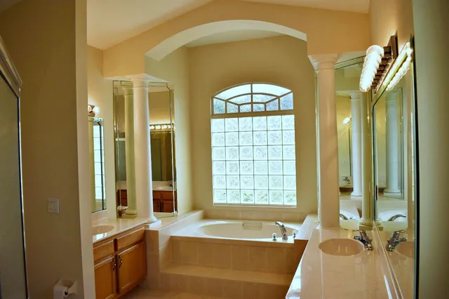 a spacious bathroom with a tub a double vanity sink and a large mirror