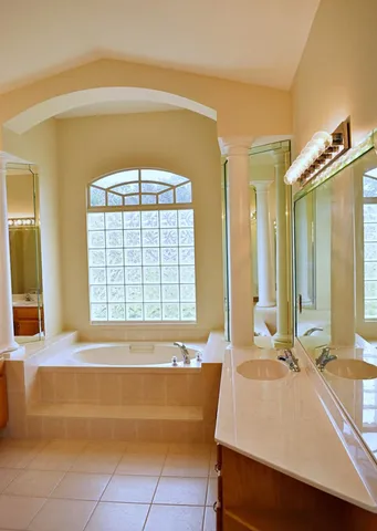 a spacious bathroom with a tub a sink and a large mirror