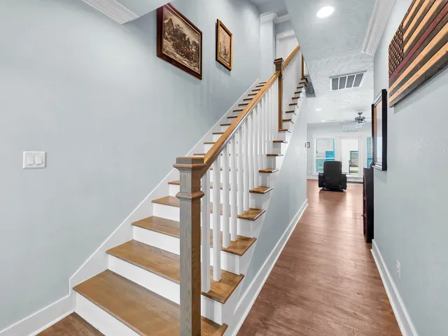 a view of staircase with lots of frames on wall and wooden floor