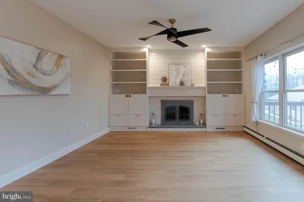 a view of an empty room with wooden floor and windows