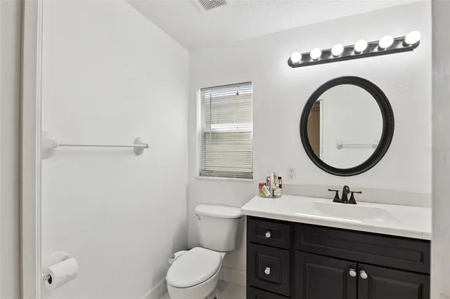 a bathroom with a toilet a sink a mirror and vanity