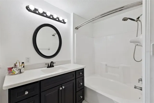 a bathroom with a sink vanity mirror and a bathtub