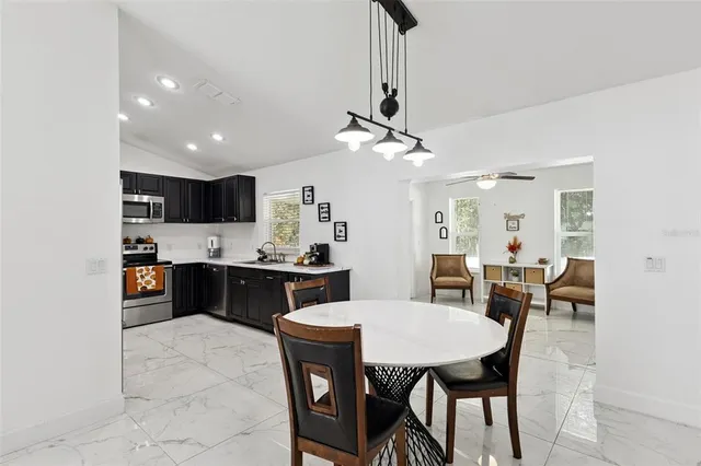 a kitchen with stainless steel appliances kitchen island granite countertop a sink a stove a table and chairs