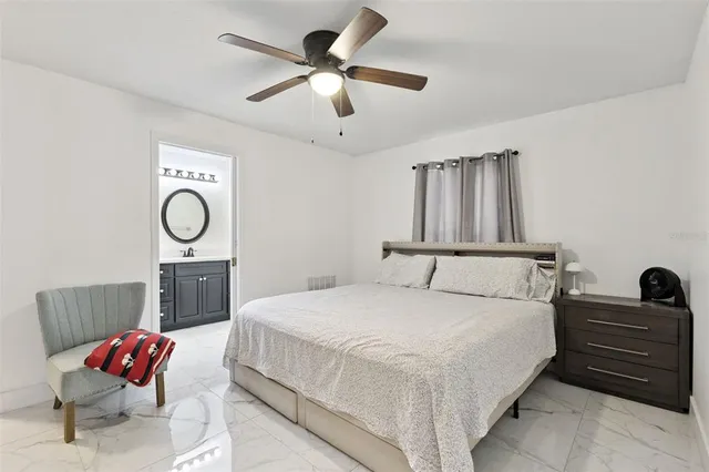 a bedroom with a bed a dresser and a chandelier