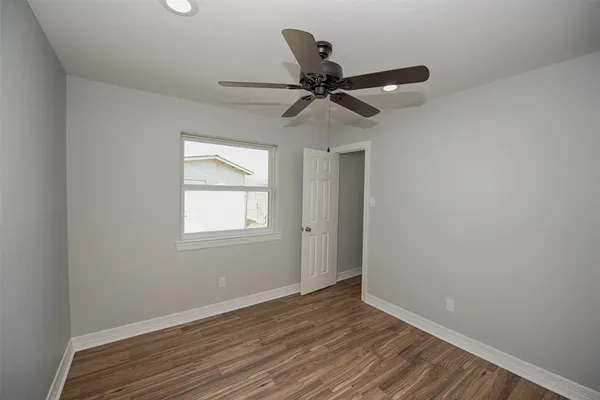 an empty room with wooden floor fan and windows