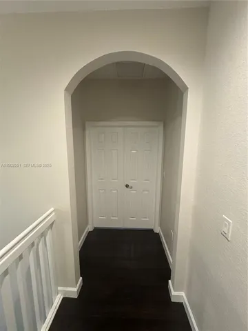 an empty room with wooden floor closet and windows