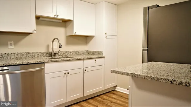 a kitchen with stainless steel appliances granite countertop a sink refrigerator and cabinets