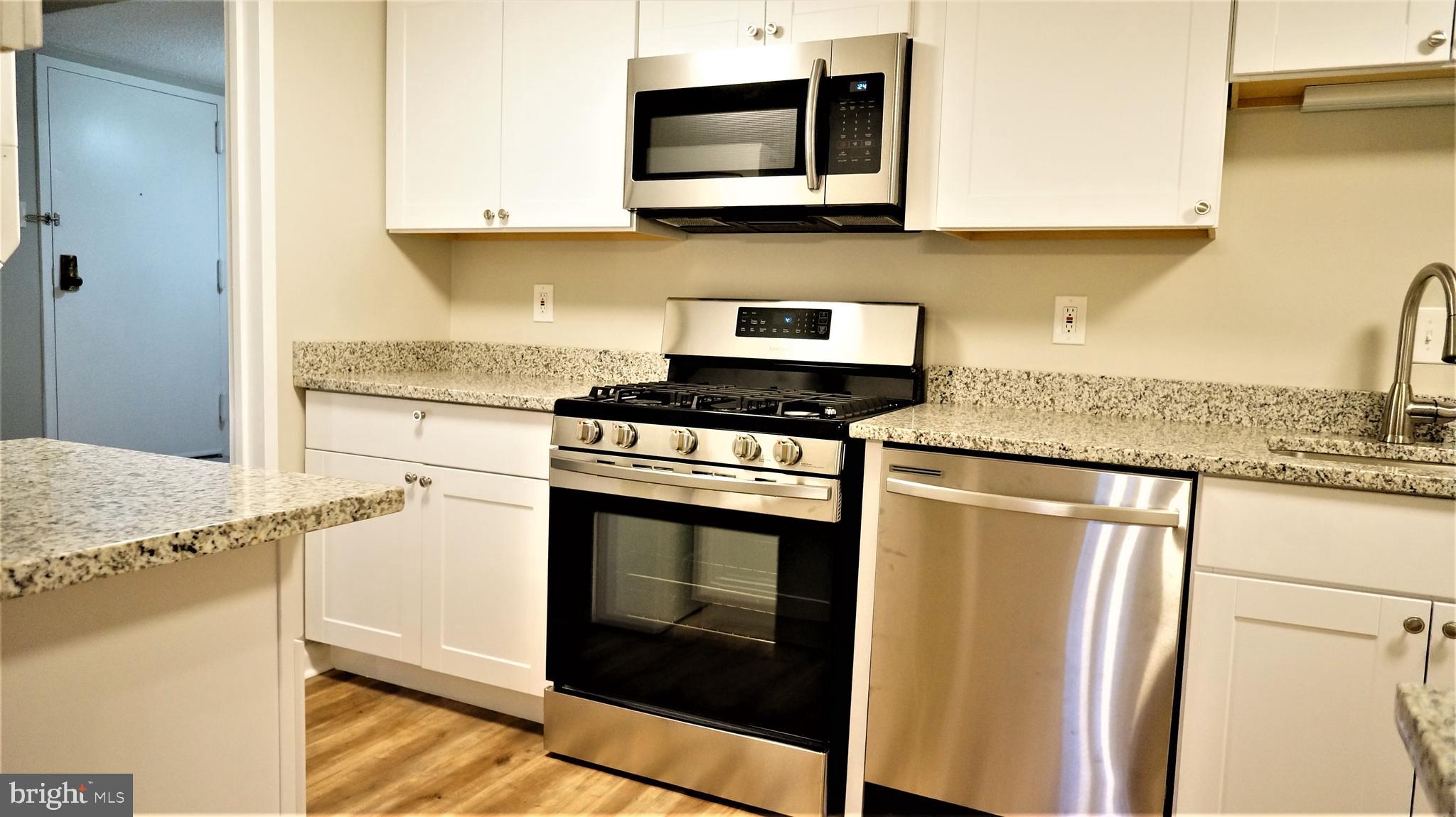 11818 Breton Court, Unit 1A Reston, VA 20191 - Photo 5 of 38 a kitchen with stainless steel appliances granite countertop a stove top oven microwave and refrigerator