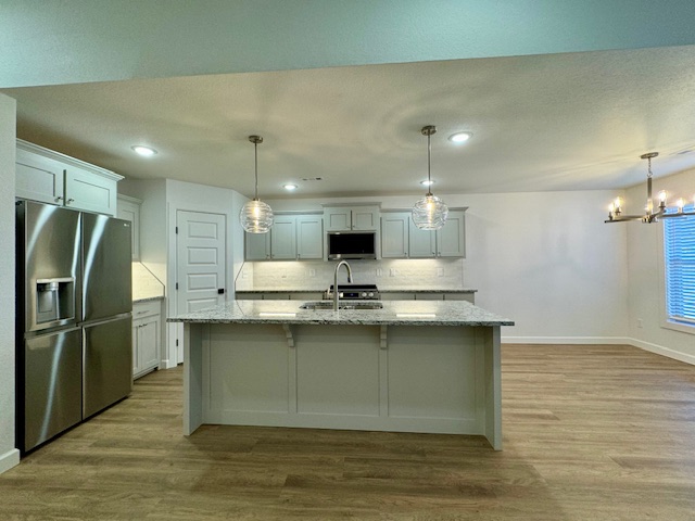 2250 Hunter Drive Pea Ridge, AR 72751 - Photo 6 of 21 Kitchen island with stone countertop, stainless steel appliances, wood-finish flooring, recessed lighting, and pendant lighting