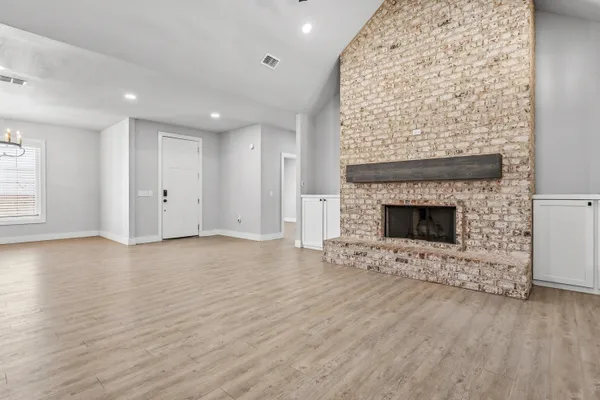 an empty room with wooden floor a fireplace and window