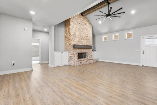 an empty room with windows fireplace and wooden floor