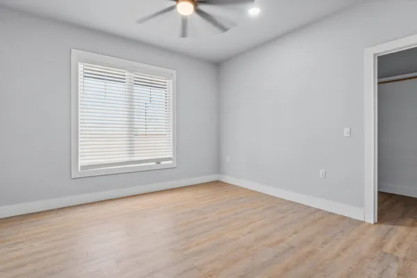 an empty room with a window and a ceiling fan