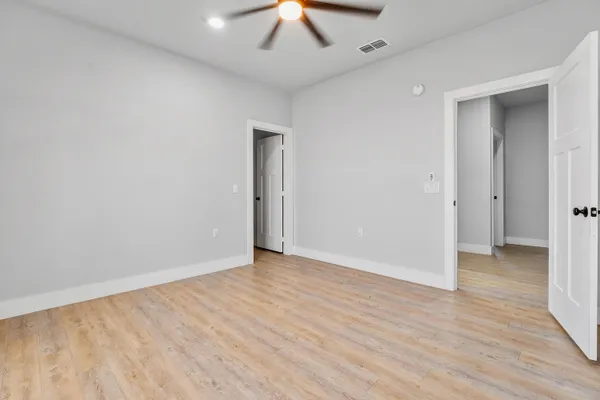 an empty room with wooden floor and a ceiling fan